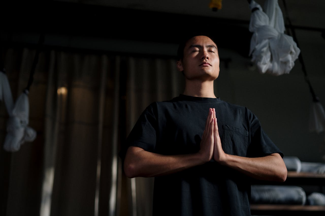 An adult male practicing meditation in a yoga studio, focusing on mindfulness and wellbeing.